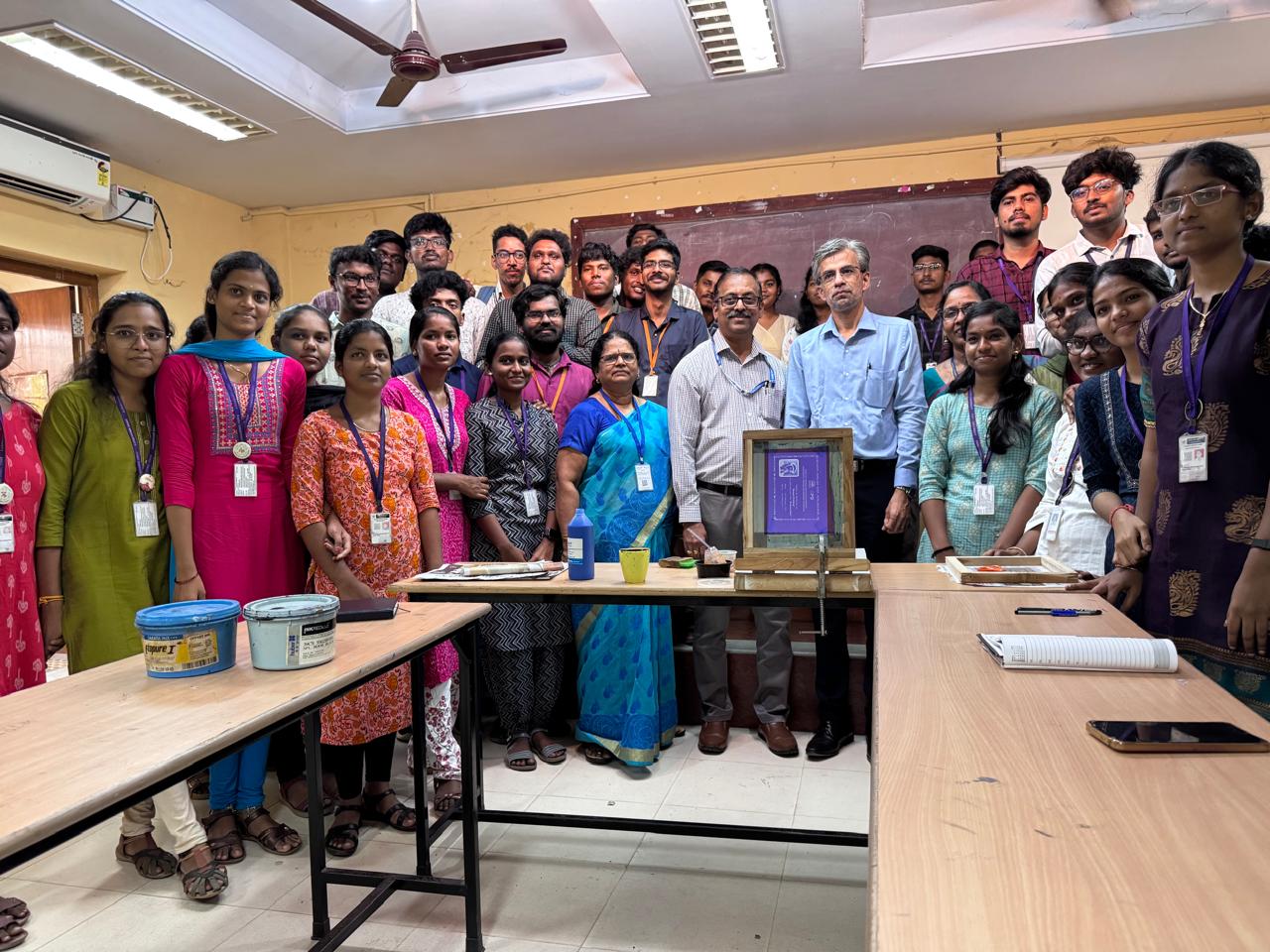 Jeetendra J demonstrating screen printing workflow with students around a press table